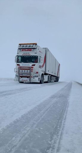 Hvit trailer på snødekt vei